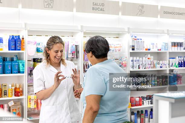 a pharmacist advises an elderly woman on medication in a pharmacy. - woman at pharmacy stock pictures, royalty-free photos & images