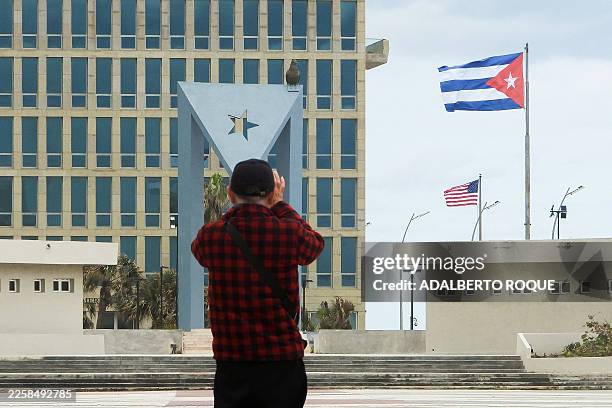 Tourist takes pictures of the US Embassy with the US flag and the Cuban flag in the background in Havana on January 30, 2026. Cuban President Miguel...