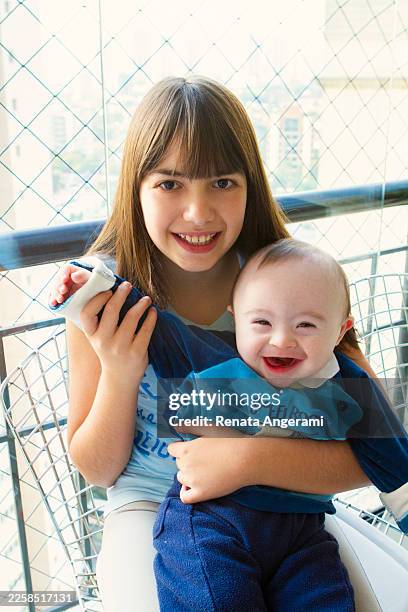 sister with her baby brother with down syndrome - caucasian 11 12 girl portrait vertical beautiful stock pictures, royalty-free photos & images
