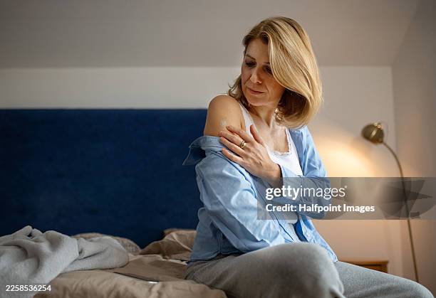 woman applying estrogen patch during hormone therapy. rear view. - hormone therapy stock pictures, royalty-free photos & images