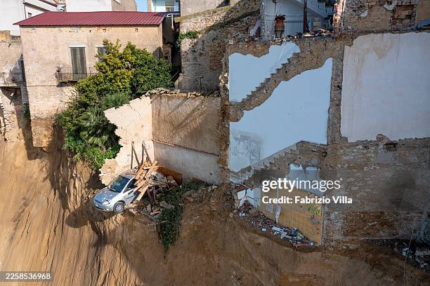 Car hangs over the void after the landslide tore through the hillside, as nearby homes bear the marks of collapse on January 27, 2026 in NISCEMI,...
