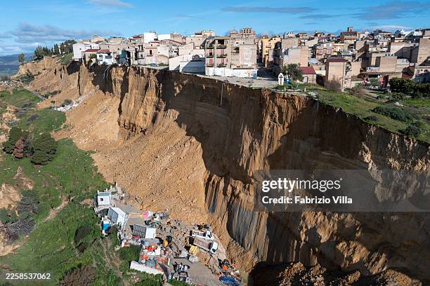 The landslide carved a vertical wall beneath the neighborhood, leaving homes facing empty space while a construction site below was engulfed by the...