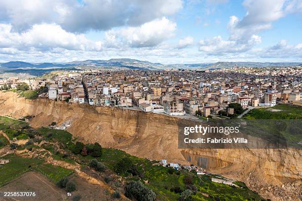 An aerial view shows a large landslide scarp along the edge of a town, with houses built close to the slope affected by ground collapse on January...