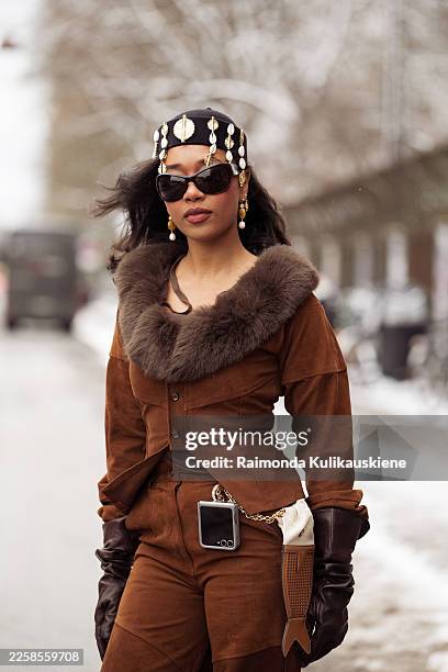 Petra Henriette Rufi wears a brown suede cropped jacket with a dark brown fur collar, matching high-waisted suede trousers, dark brown leather...