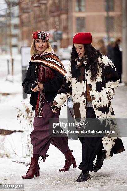 Guest wears a black coat, a multicolour patterned knit shawl, a matching knit hat, a burgundy midi skirt, burgundy heeled ankle boots and carries a...