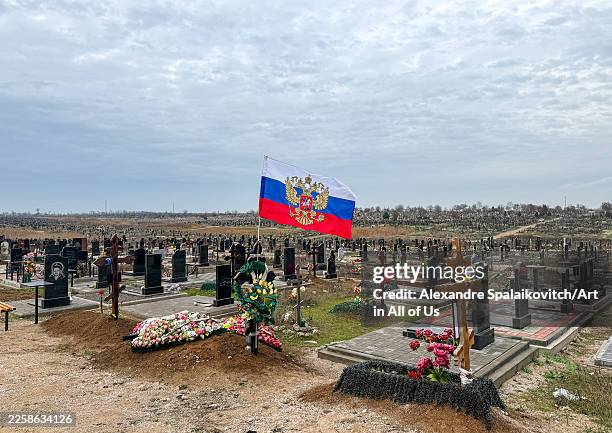 Russian flag waving over an orthodox cemetery, Donetsk Oblast, Mariupol, Ukraine on November 24, 2025 in Mariupol, Ukraine.