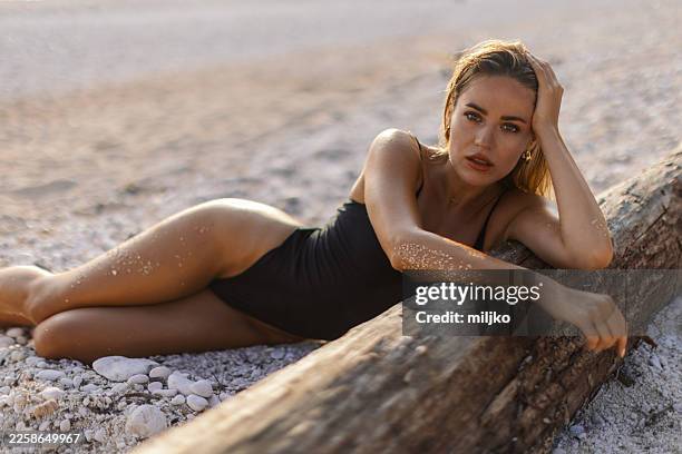 woman in a swimsuit is lying on beach, relaxing - one piece swimsuit stock pictures, royalty-free photos & images