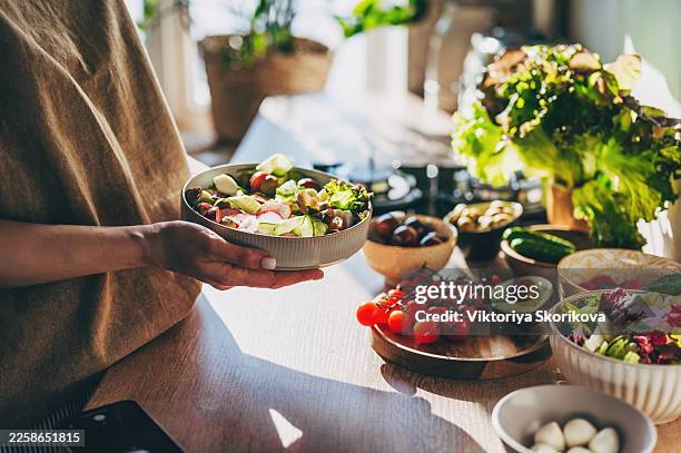 healthy dinner or lunch. woman in t-shirt and jeans eating vegan super bowl or buddha bowl with hummus, vegetable, salad, beans, couscous and avocado - fibra fotografías e imágenes de stock
