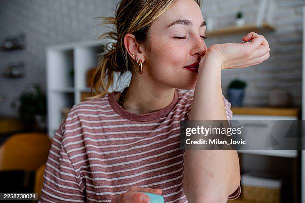 woman testing fragrance during daily beauty routine - ruiken stockfoto's en -beelden