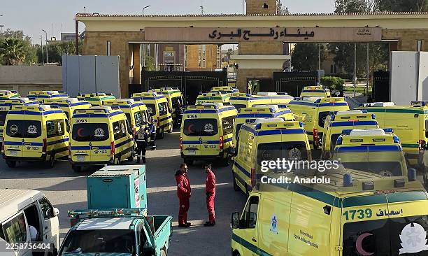 Ambulances and medical teams affiliated with the Egyptian Ministry of Health arrive at the Rafah Border Crossing on the Egypt-Gaza border, standing...