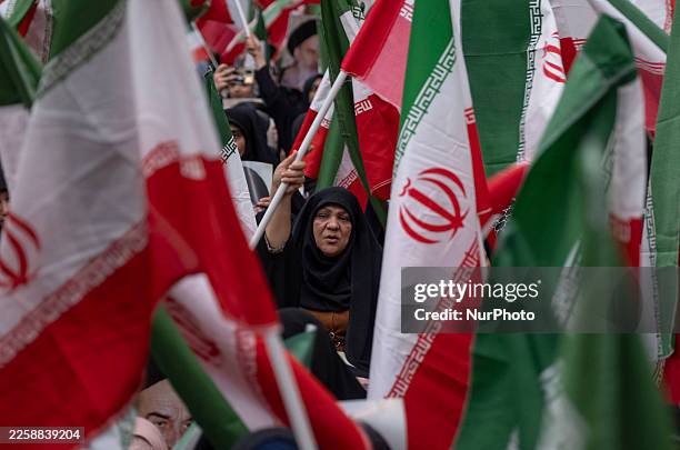 Veiled Iranian woman waves a country flag while participating in a ceremony marking the 47th anniversary of the victory of Iran's Islamic Revolution...