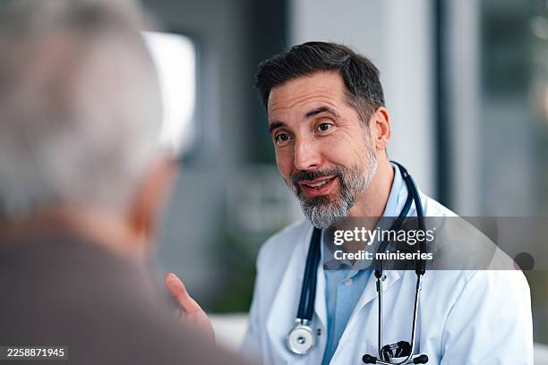 experienced doctor speaking with senior patient in a clinic setting, friendly medical conversation - geduld stockfoto's en -beelden