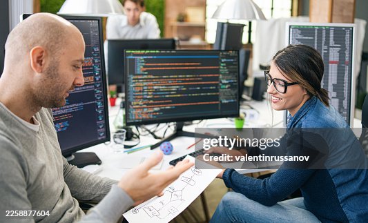 Developers collaborating on program coding flowcharts in office Developers collaborating on program coding flowcharts in office