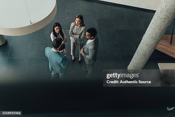 group of colleagues discuss ideas in modern corporate lobby during business meeting - styrelse bildbanksfoton och bilder
