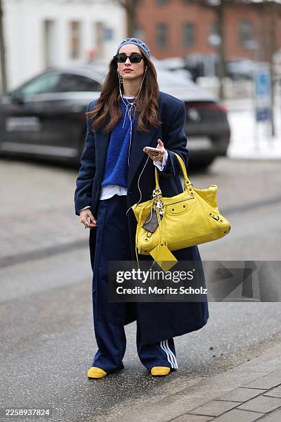Evi Wave is seen wearing a long navy blue single breasted wool coat with a tailored silhouette and notch lapels from Aylin Koenig; navy blue wide leg...