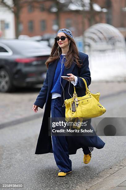 Evi Wave is seen wearing a long navy blue single breasted wool coat with a tailored silhouette and notch lapels from Aylin Koenig; navy blue wide leg...