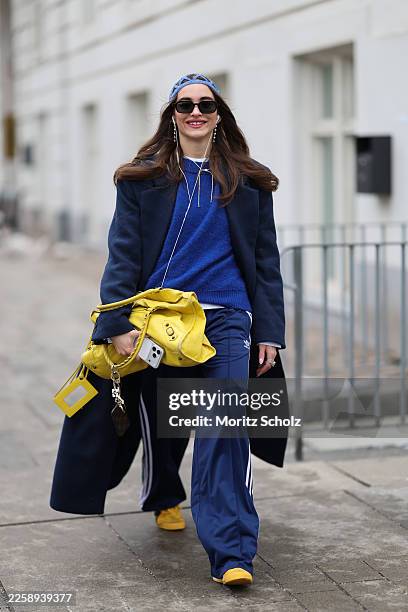 Evi Wave is seen wearing a long navy blue single breasted wool coat with a tailored silhouette and notch lapels from Aylin Koenig; navy blue wide leg...