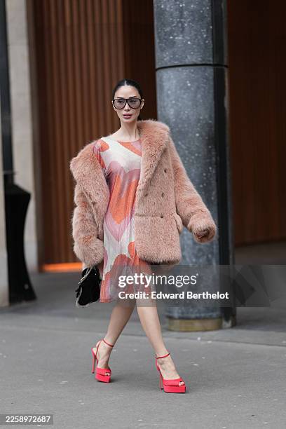 Heart Evangelista wears black hair slicked back into a low bun with a center part, oversized square sunglasses with black frames and gray gradient...