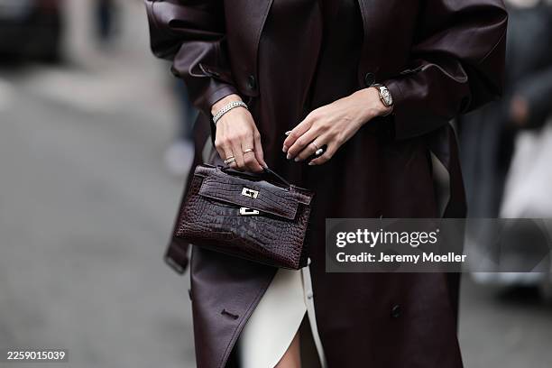 Leonie Hanne seen wearing an effortlessly polished street-style look featuring an oversized deep burgundy leather trench coat with dramatic...