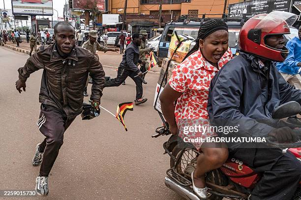 Ugandan police officers attempt to arrest opposition supporters taking part in a demonstration against alleged election fraud and in support of...