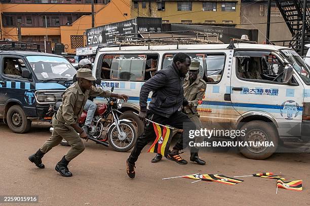 Ugandan police officers attempt to arrest an opposition supporter taking part in a demonstration against alleged election fraud and in support of...