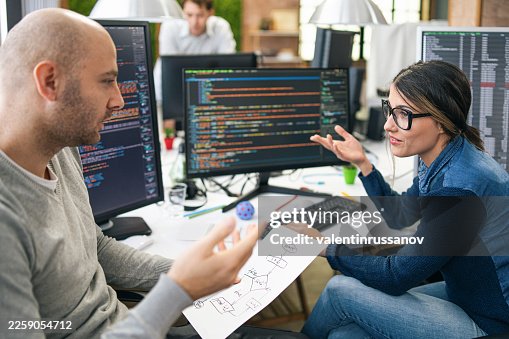 Developers collaborating on program coding flowcharts in office Developers collaborating on program coding flowcharts in office
