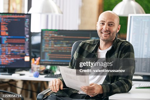 Developer smiling while coding program on computer at modern office Developer smiling while coding program on computer at modern office