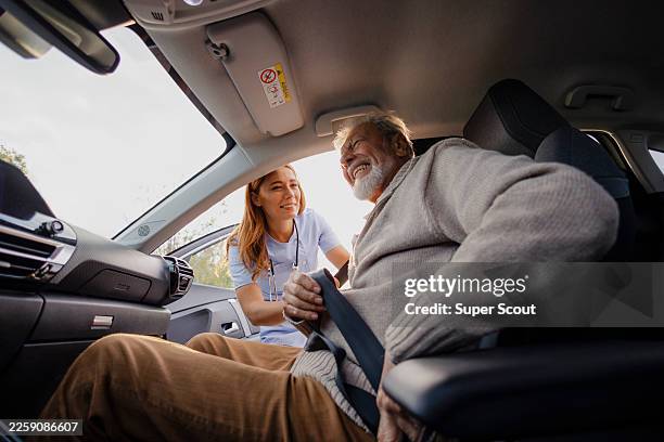 caregiver helping elderly man fasten seat belt in car - man closing car door stock pictures, royalty-free photos & images