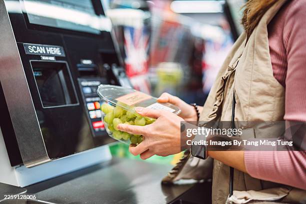 woman using self checkout while buying fresh fruit in supermarket - self service stock pictures, royalty-free photos & images