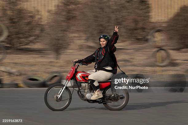 Young Iranian woman, Bahar demonstrates the Victory sign while riding a motorcycle during a training session at the Motorex Motorcycle Training...