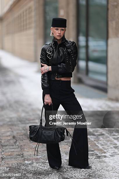Ava Black seen wearing a black pillbox style hat, cropped black leather jacket by Alexander McQueen, featuring a structured silhouette with bold...