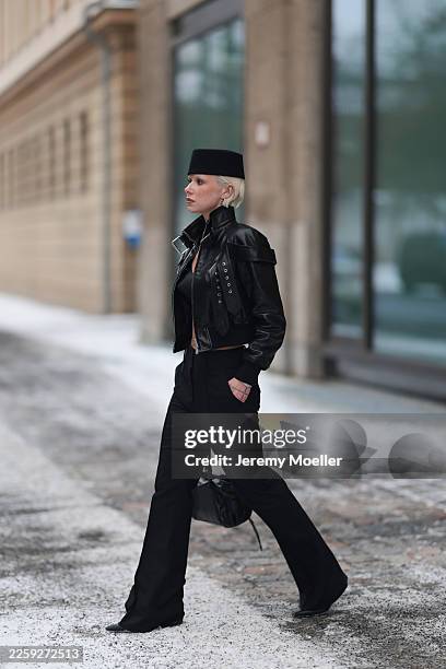 Ava Black seen wearing a black pillbox style hat, cropped black leather jacket by Alexander McQueen, featuring a structured silhouette with bold...