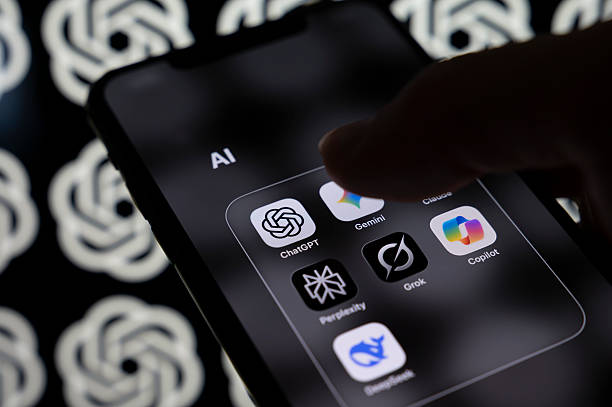 Smartphone screen displays a folder containing the AI applications Claude, ChatGPT, Gemini, Perplexity, Grok, Copilot, and DeepSeek with a multitude...