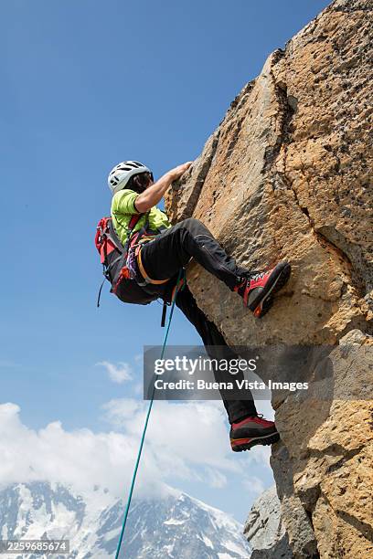 male mountaineer climbing a rugged mountain rocky ridge - sport climber stock pictures, royalty-free photos & images