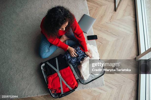 a black woman packs a suitcase. packing a suitcase. unpacking clothes from a suitcase. a list of things to take with you on a trip. - rote schuhe stock-fotos und bilder