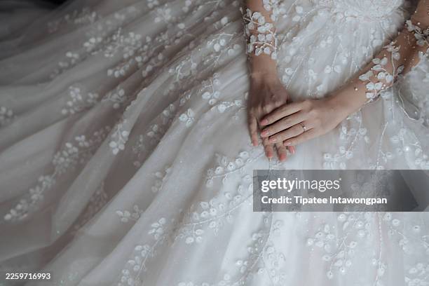junge asiatische braut im spitzenkleid genießt einen moment drinnen während der hochzeitszeremonie mit luxuriöser dekoration. hochzeitstag und feiermoment. - hochzeitskleid stock-fotos und bilder