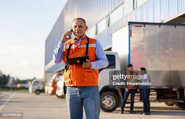 employé parlant au téléphone tout en envoyant des camions à un quai de chargement - parc automobile photos et images de collection