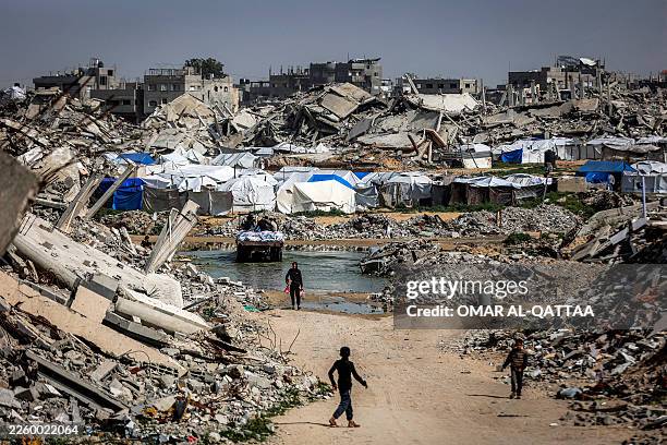Boys walk past the rubble of destroyed buildings in the Jabalia camp for Palestinian refugees in the northern Gaza Strip on February 8, 2026. Since...