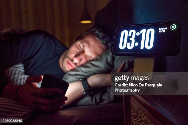 man awake in bed checking smartphone at night - number 3 stock pictures, royalty-free photos & images