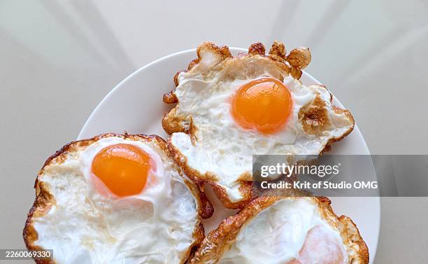 sunny side up eggs with crispy edges in natural light - fried egg stock pictures, royalty-free photos & images