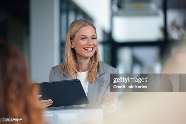 confident female speaker delivers conference presentation with tablet to engaged audience at summit - spokesperson stock pictures, royalty-free photos & images