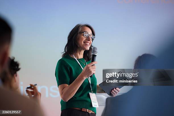 confident female speaker delivers engaging conference talk to an attentive audience - presenter stock pictures, royalty-free photos & images