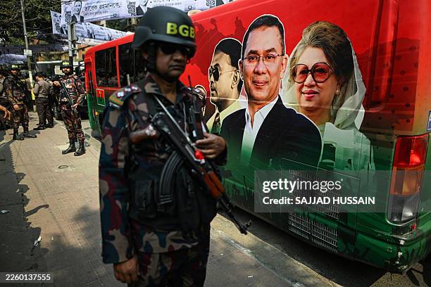 Border Guard Bangladesh personnel stand guard next to a bullet proof bus of Bangladesh Nationalist Party chairman and election candidate Tarique...