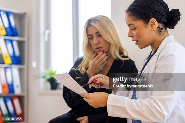 female doctor explaining medical results on paper to concerned patient - medical test results stock pictures, royalty-free photos & images