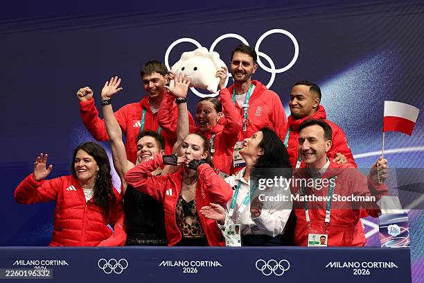 Sofiia Dovhal and partner Wiktor Kulesza of Team Poland react with their team in the Kiss and Cry zone after competing in the Ice Dance - Rhythm...