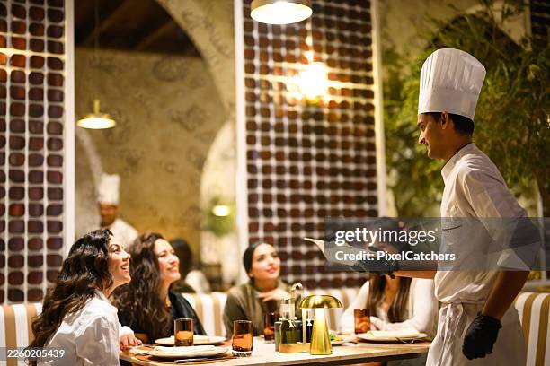 arab chef presenting dishes to group of women in upscale restaurant - indian restaurant stock pictures, royalty-free photos & images