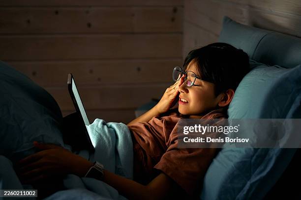boy rubbing tired eyes using digital tablet in bed at night - kid rubbing eyes stock pictures, royalty-free photos & images
