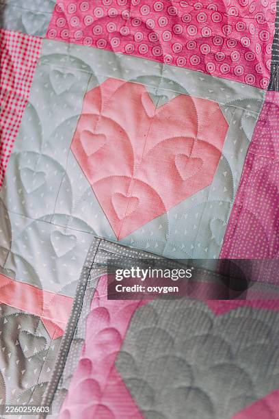 soft pastel quilted heart patchwork textile closeup background. detailed closeup of pillow pink and grey patchwork quilt blocks featuring layered quilted hearts and delicate dot fabrics. - patchwork quilt stock pictures, royalty-free photos & images