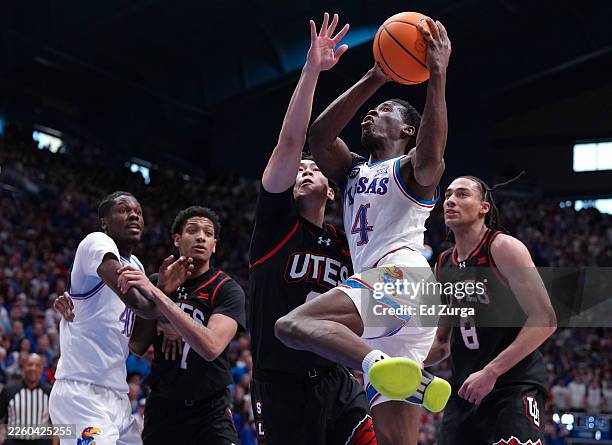 Guard Melvin Council Jr. #14 of the Kansas Jayhawks drives to the basket against guard Jerry Huang of the Utah Utes and forward Keanu Dawes of the...