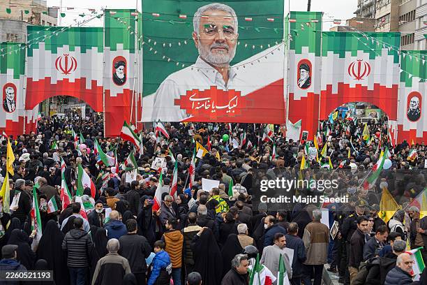 Iranian participants march with a background of Qassem Soleimani's poster during commemorations to mark the anniversary of the 1979 Iranian...